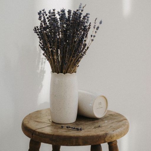 Photographie d’intérieur : bouquet de lavande dans un vase en céramique, posé sur un tabouret ancien