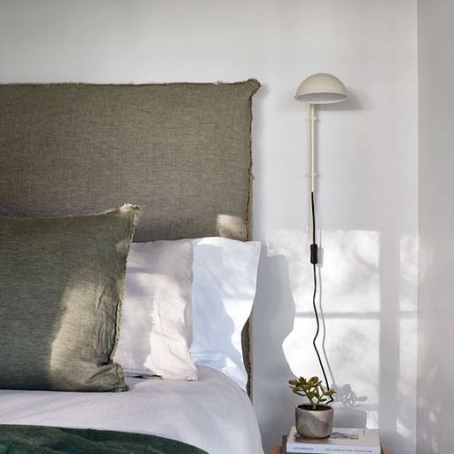 Photographie d’intérieur : tête de lit et draps dans des tons de vert kaki, blanc, et rose poudré
