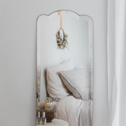 Photographie d’intérieur : lit beige qui se reflète dans un miroir ancien