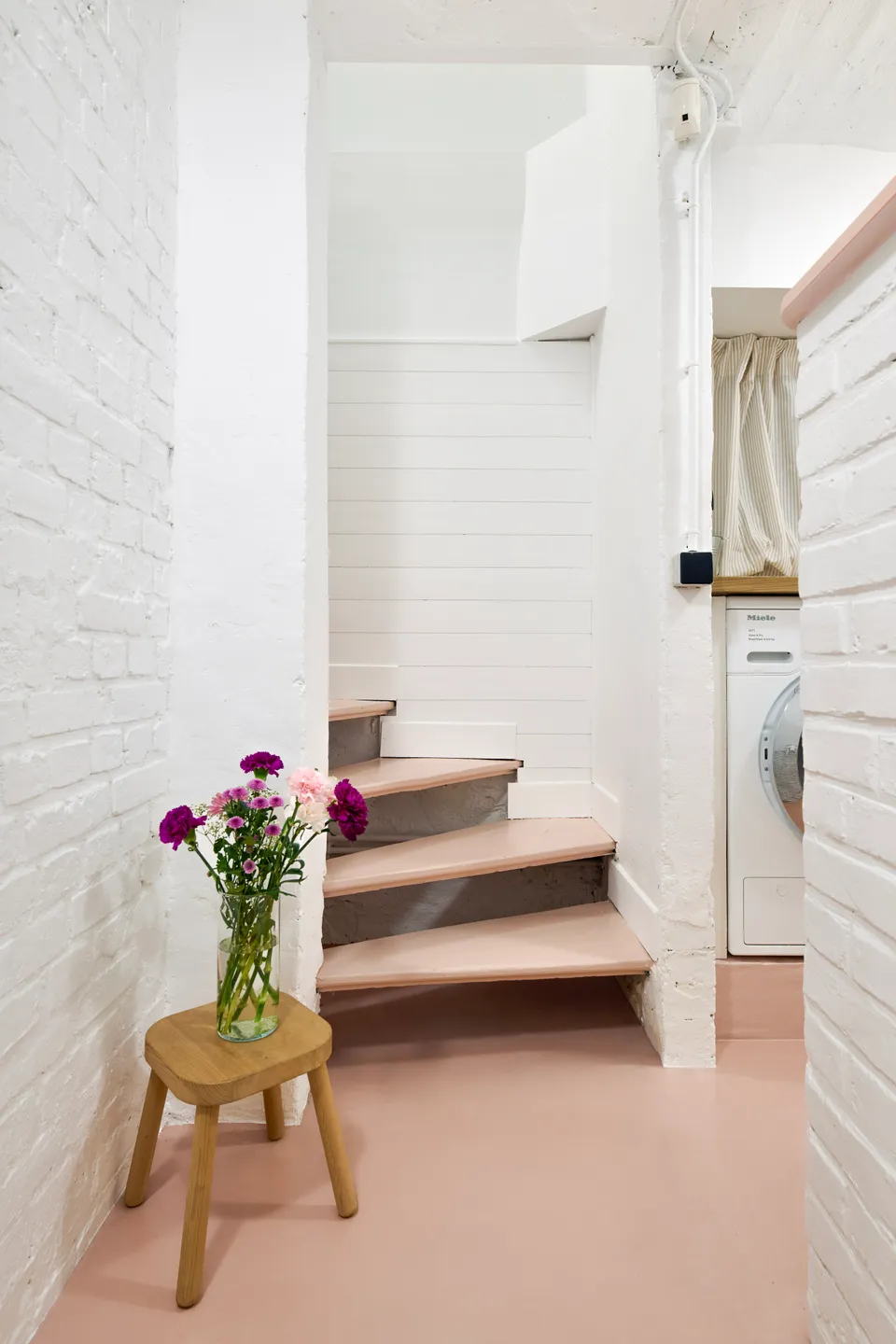 Studio Madame : architecte d’intérieur, Paris et Montmorency.
Projet réalisé à Deuil-la-Barre.
Photographie d’intérieur : escalier menant au sous-sol entièrement repeint en blanc sur les murs (Ressource) et en rose sur les marches. Le sous-sol présente toutes les caractéristiques typiques d’une meulière (plafond voûté, tuyaux apparents, briques, etc.). Les murs sont peints en blanc (Ressource) et le sol est habillé d’un béton ciré rose (Harmony Béton).