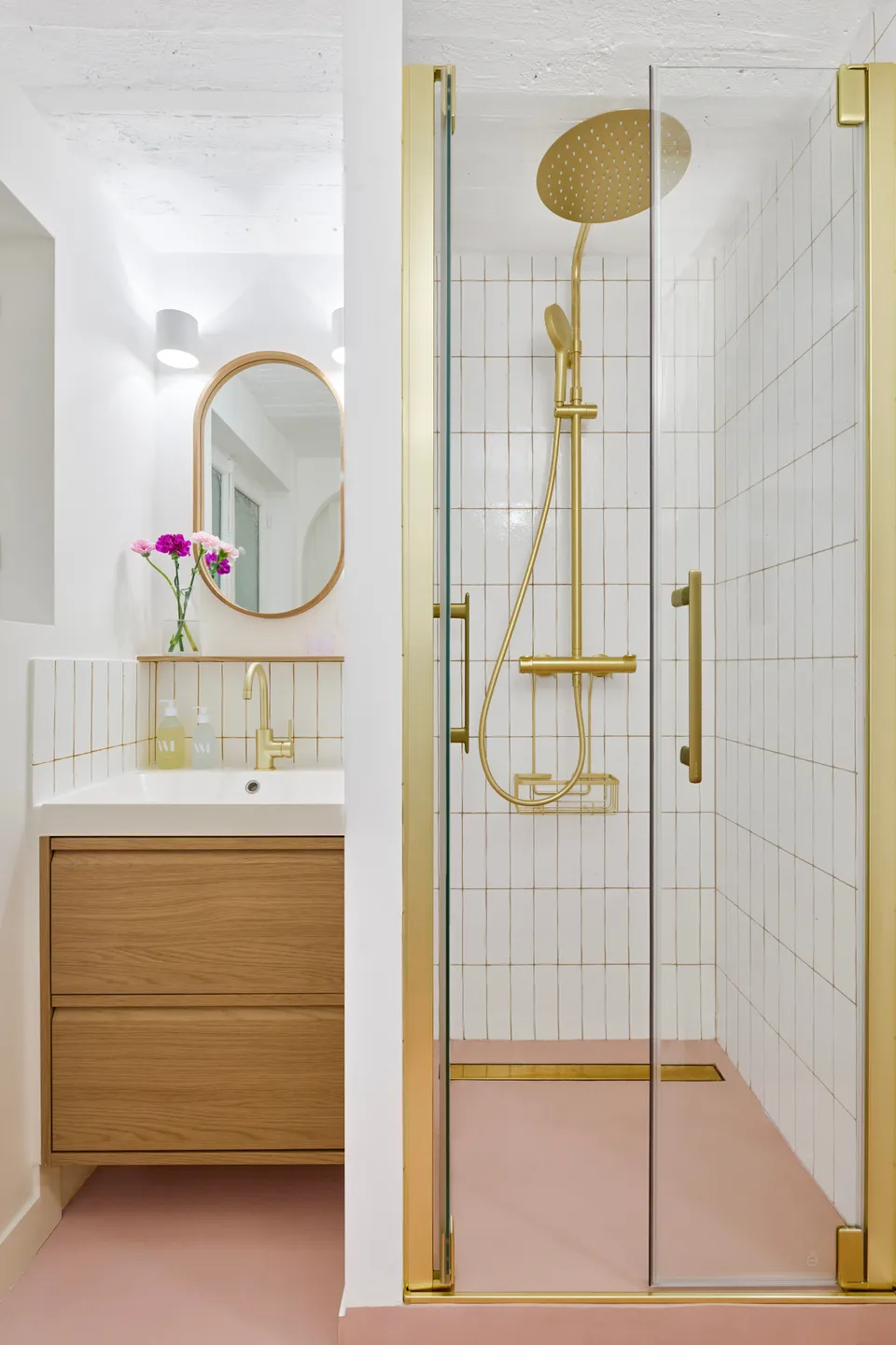 Studio Madame : architecte d’intérieur, Paris et Montmorency.
Projet réalisé à Deuil-la-Barre.
Photographie d’intérieur : petite salle de bain composée d’un espace vasque avec meuble en chêne, mitigeur doré, tablette/étagère et miroir en chêne ainsi que d’un espace douche avec portes de douche et robinetterie dorées. Les murs sont peints en blanc (Ressource) et carrelés d’une faïence artisanale blanche avec des joints jaune ocre, le sol, lui, est habillé d’un béton ciré rose (Harmony Béton).