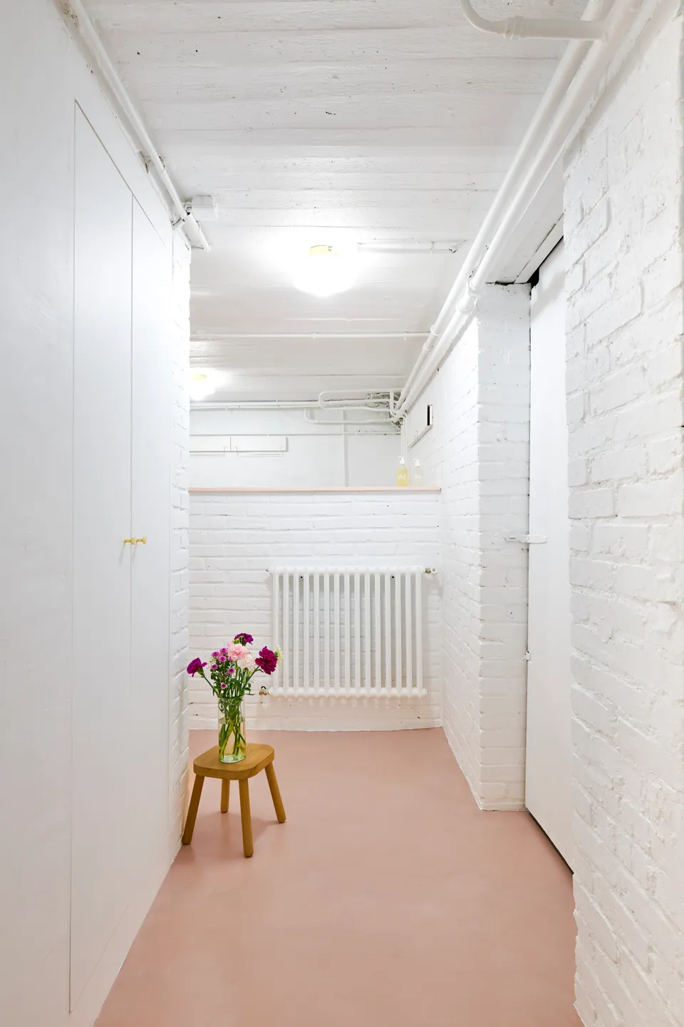 Studio Madame : architecte d’intérieur, Paris et Montmorency.
Projet réalisé à Deuil-la-Barre.
Photographie d’intérieur : couloir entièrement repeint en blanc (Ressource), intégrant un placard réalisé sur mesure. Le sous-sol présente toutes les caractéristiques typiques d’une meulière (plafond voûté, tuyaux apparents, briques, etc.). Les murs sont peints en blanc (Ressource) et le sol est habillé d’un béton ciré rose (Harmony Béton).