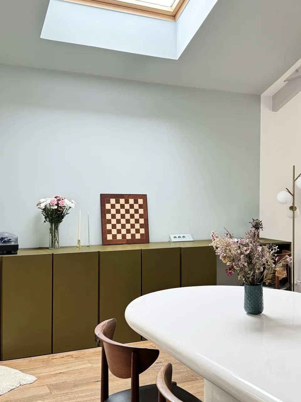 Studio Madame : architecte d’intérieur, Paris et Enghien-les-Bains.
Projet réalisé à Deuil-la-Barre.
Photographie d’intérieur : détail de la salle à manger d'une ancienne meulière rénovée à Deuil-la-Barre avec table en résine blanche, chaises design, incluant un bureau sur mesure vert bronze délimité par une alcôve formée par un mur et un plafond bleu pâle.