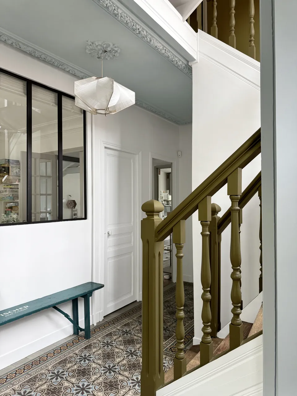 Studio Madame : architecte d’intérieur, Paris et Enghien-les-Bains.
Projet réalisé à Deuil-la-Barre.
Photographie d’intérieur : entrée d'une ancienne meulière rénovée à Deuil-la-Barre avec escalier ancien, moulures, plafond sculpté bleu pâle, banc ancien et carreaux de ciment d’origine au sol.