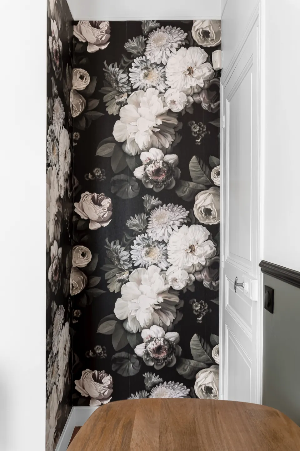 Studio Madame : architecte d’intérieur, Paris et Montmorency
Projet réalisé à Enghien-les-Bains.
Photographie d’intérieur : entrée de la pièce (bureau) mise en valeur par un papier peint foncé à fleurs en contraste avec l’autre mur blanc orné d’un soubassement vert foncé. Porte ancienne de type haussmannien, repeinte en blanc.