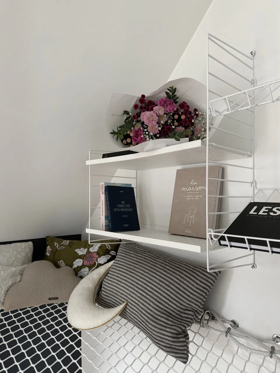 Studio Madame : architecte d’intérieur, Paris et Montmorency
Projet réalisé à Enghien-les-Bains.
Photographie d’intérieur : coin lecture sur filet mezzanine suspendu composé de coussins colorés et d’étagères fines blanches sur lesquelles reposent des livres et un bouquet de fleurs.