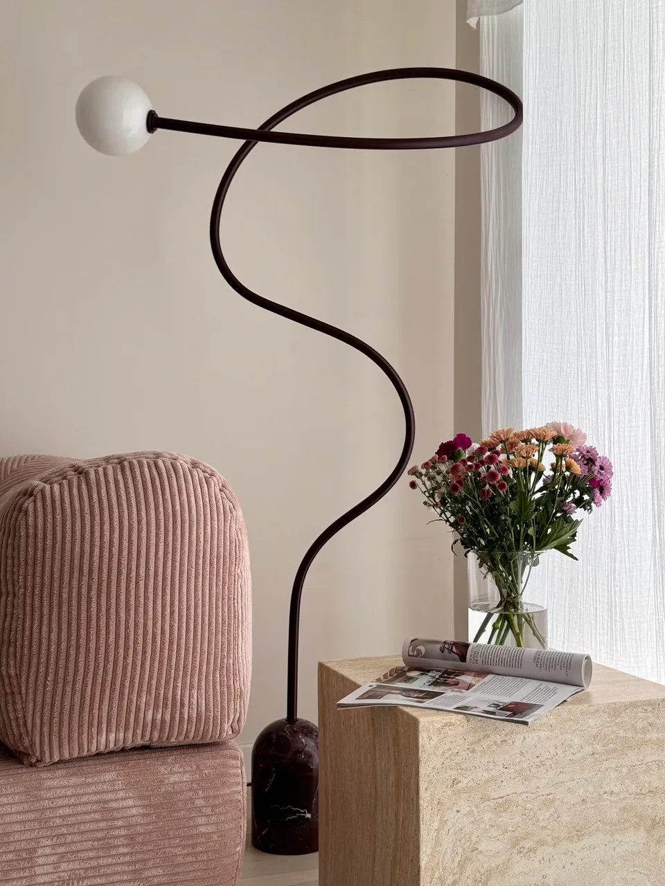 Studio Madame : architecte d’intérieur, Paris et Montmorency
Projet réalisé à Montmorency.
Photographie d’intérieur : salon composé d’un canapé rose, d’une lampe sur pied de couleur bordeaux, d’une petite table d’appoint en travertin sur laquelle reposent un bouquet de fleurs et un magazine de décoration.