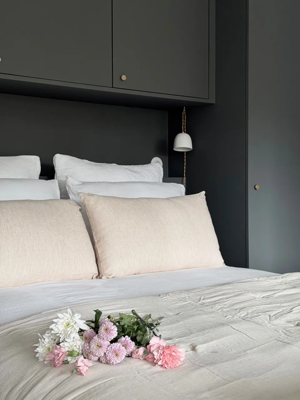 Studio Madame : architecte d’intérieur, Paris et Montmorency
Projet réalisé à Montmorency.
Photographie d’intérieur : chambre parentale avec dressing réalisé sur mesure.
Le dressing est peint dans un gris-vert foncé (Down Pipe - F&B).
Le lit est habillé d’une parure blanche en gaze de coton, de coussins et édredon beiges.
La prise ainsi que les baladeuses sont en porcelaine.
Des fleurs sont posées sur le lit.