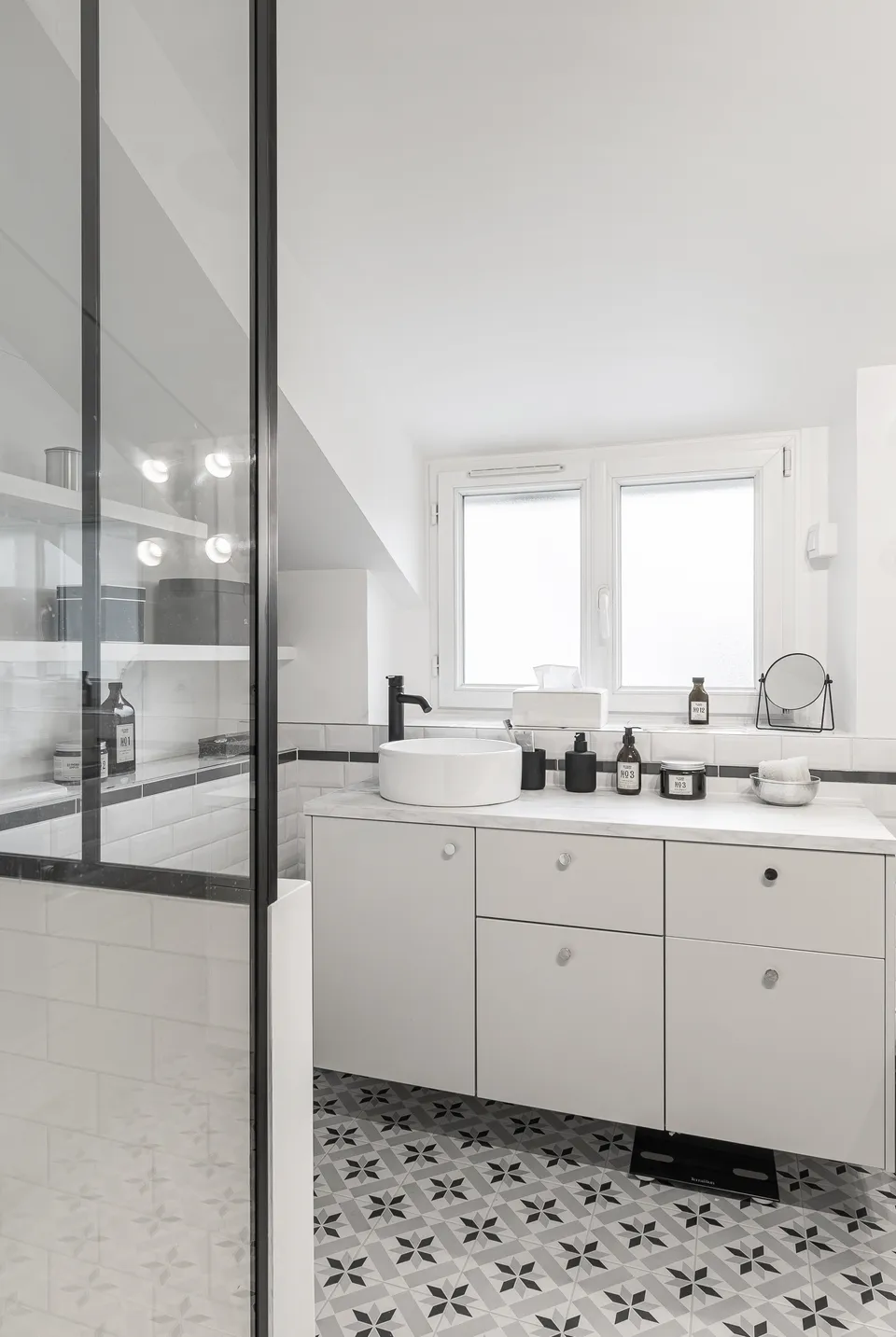 Studio Madame : architecte d’intérieur, Paris et Montmorency
Projet réalisé à Enghien-les-Bains.
Photographie d’intérieur : salle de bain aux tons noir et blanc avec verrière noire, carreaux de métro en faïence et carrelage imitation carreaux de ciment au sol.