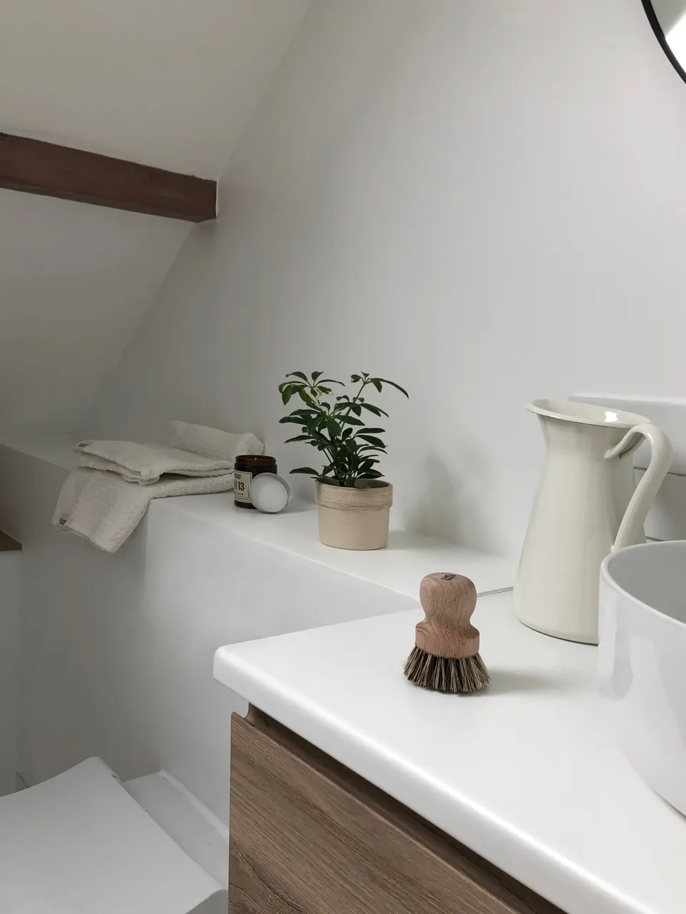 Studio Madame : architecte d’intérieur, Paris et Montmorency
Projet réalisé à Saint-Gratien.
Photographie d’intérieur : salle de bain sous pente avec coffrage réalisé dans l’alignement du meuble vasque, sur lequel repose une plante, une bougie et des draps de bain.