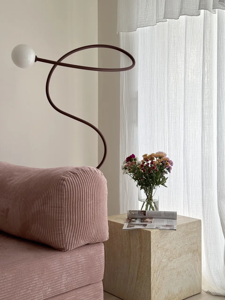 Studio Madame : architecte d’intérieur, Paris et Montmorency
Projet réalisé à Montmorency.
Photographie d’intérieur : salon composé d’un canapé rose, d’une lampe sur pied de couleur bordeaux, d’une petite table d’appoint en travertin sur laquelle reposent un bouquet de fleurs et un magazine de décoration.