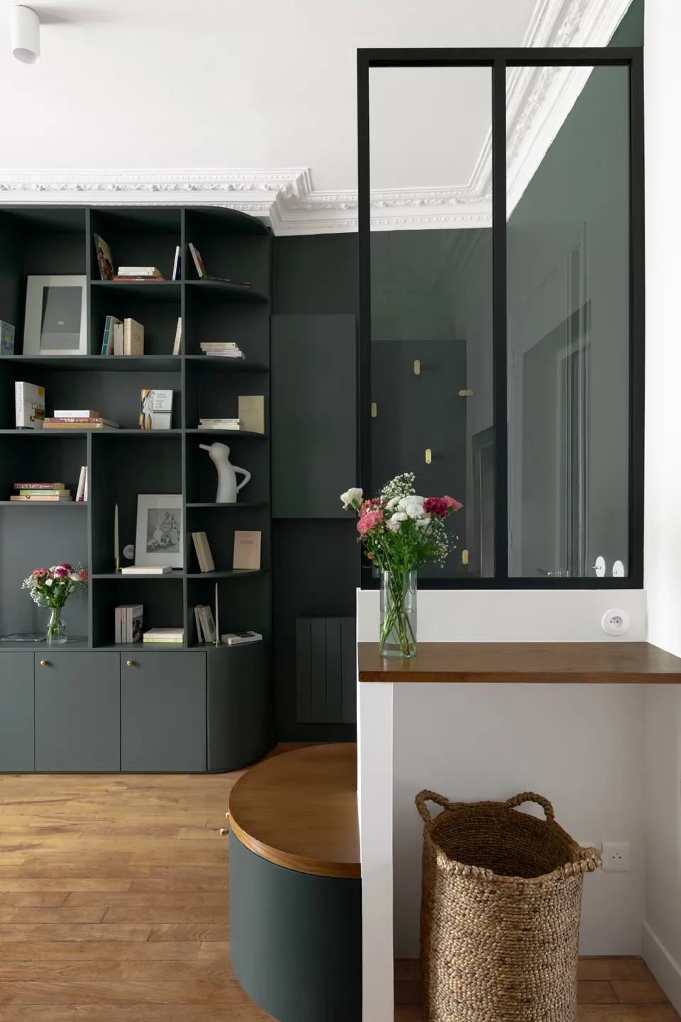 Studio Madame : architecte d’intérieur, Paris et Montmorency.
Projet réalisé à Boulogne-Billancourt. 
Photographie d’intérieur : entrée entièrement peinte en vert foncé (Ressource) incluant une majestueuse bibliothèque réalisée sur mesure et donnant sur un espace ouvert avec salon, salle à manger et cuisine.
L’entrée est composée d’une banquette arrondie réalisée sur mesure et d’une verrière noire. 
Les autres murs sont peints en blanc (Ressource) et un parquet massif ancien est au sol.