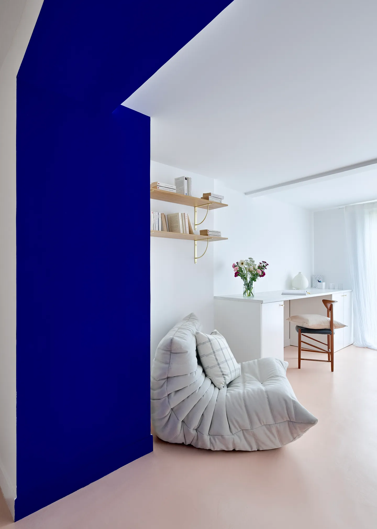 Studio Madame : architecte d’intérieur, Paris et Montmorency.
Projet réalisé à Deuil-la-Barre.
Photographie d’intérieur : arche peinte en bleu Klein (Ressource) amenant sur un bureau blanc réalisé sur mesure (Plum Living) agrémenté d’un plateau marbre, de poignées dorées et d’une chaise minimaliste en bois. Deux étagères chêne montées sur équerres dorées et un fauteuil Togo gris perle (Ligne Roset) forment un petit espace lecture. Les murs sont peints en blanc et bleu Klein (Ressource) et le sol est habillé d’un béton ciré rose (Harmony Béton).