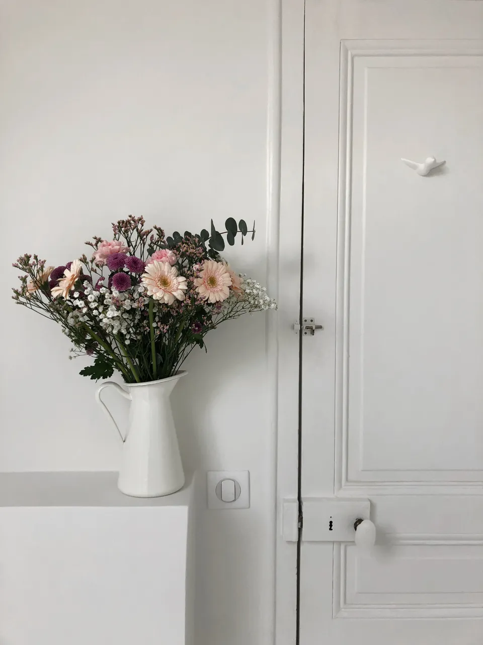 Studio Madame : architecte d’intérieur, Paris et Montmorency
Projet réalisé à Cormeilles-en-Parisis.
Photographie d’intérieur : bouquet de fleurs dans des tons rose, blanc et mauve et patères en céramique en forme d’oiseau fixées sur une porte ancienne.