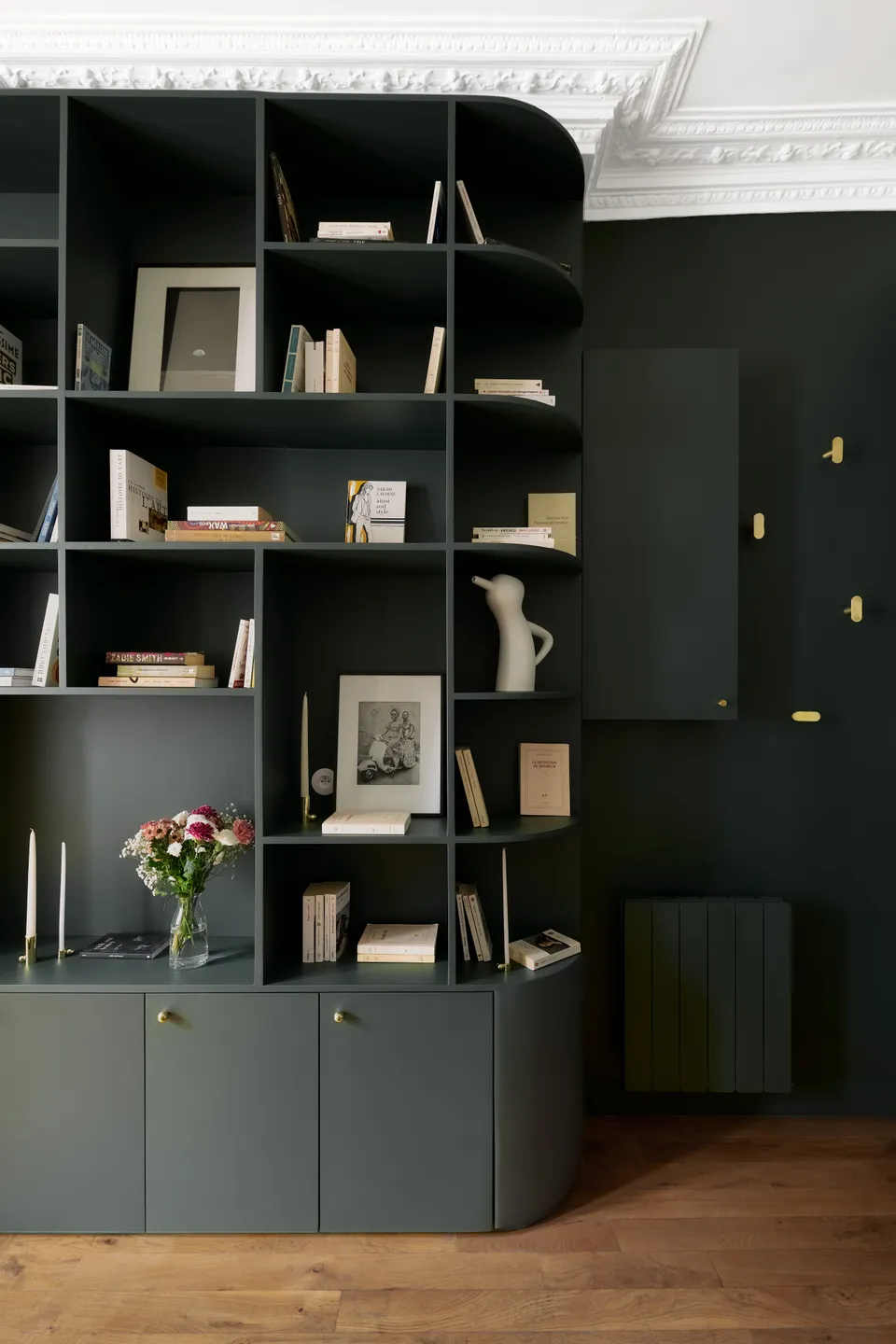 Studio Madame : architecte d’intérieur, Paris et Montmorency.
Projet réalisé à Boulogne-Billancourt. 
Photographie d’intérieur : entrée entièrement peinte en vert foncé (Ressource) incluant une majestueuse bibliothèque réalisée sur mesure.
Des patères dorées habillent le mur.
Les autres murs sont peints en blanc (Ressource) et un parquet massif ancien est au sol.